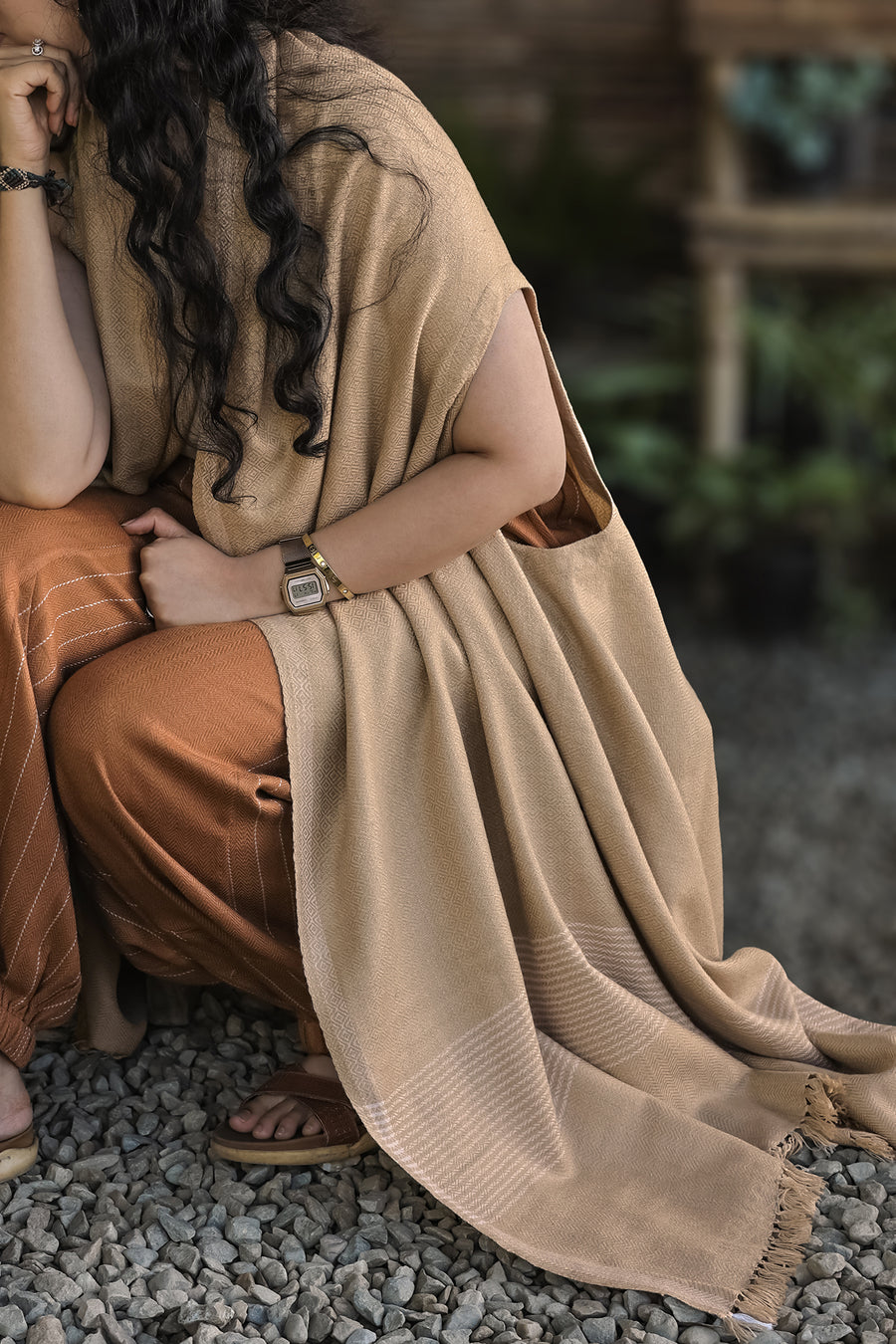 Drape Cape – Sand Beige, the fringed edge falling to the ground as she crouches